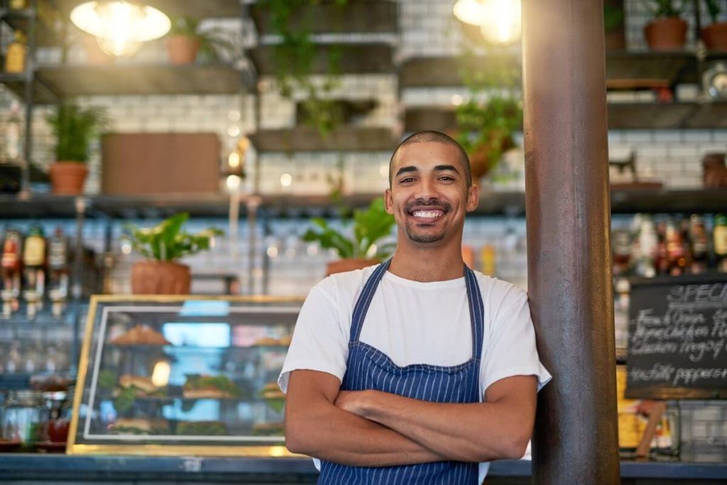 business owner smiling with arms crossed in front of business