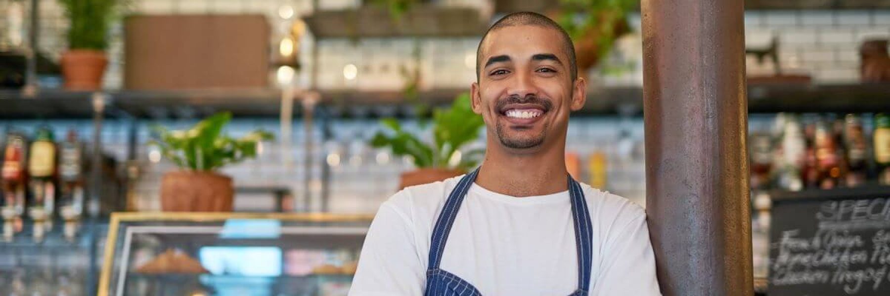 business owner smiling with arms crossed in front of business